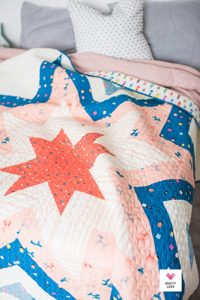 Ruby Star Society Expanding Stars quilt on bed.