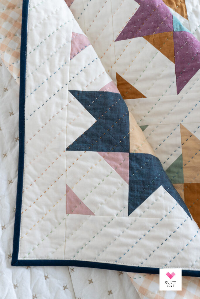 Corner of a star quilt showing the rainbow of hand quilting.