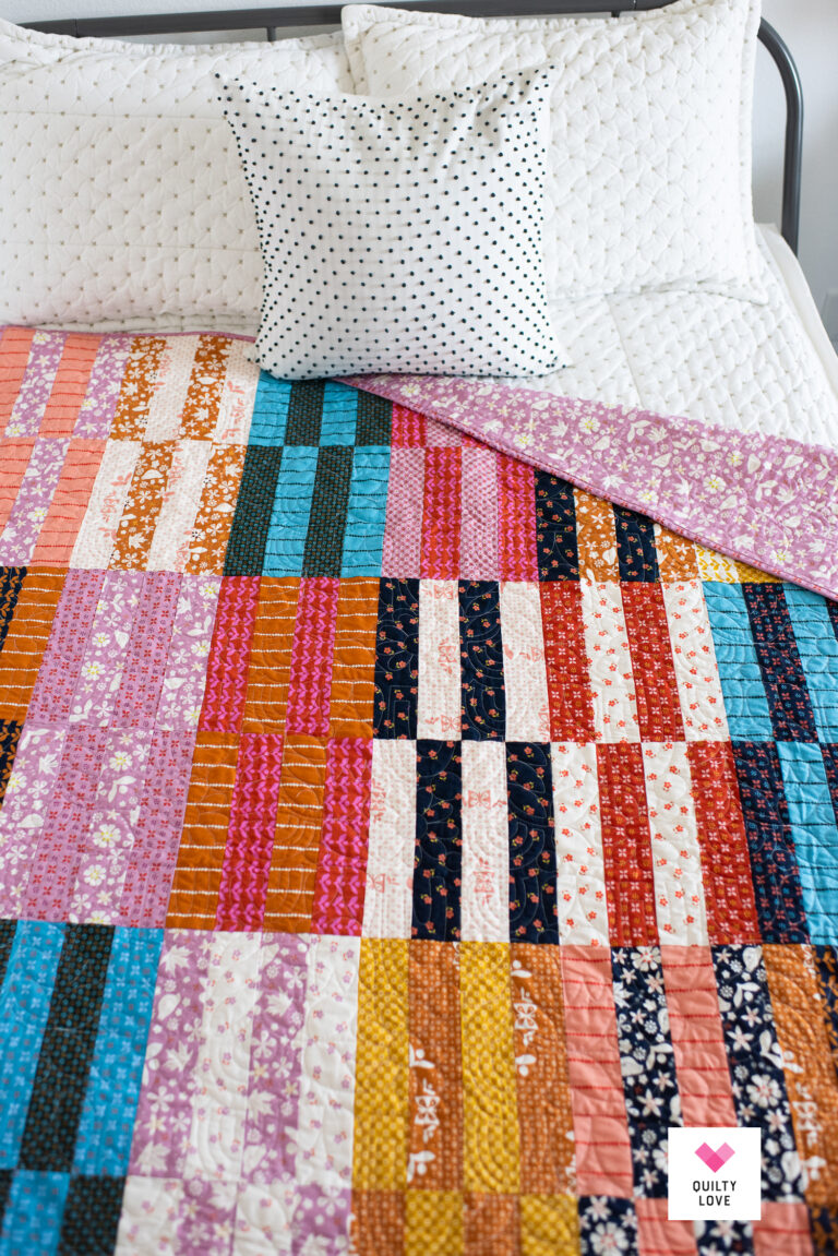 Jelly Stripes quilt made with Sugar Maple Jelly roll by Ruby Star Society styled on bed.