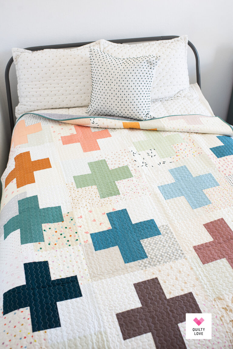 Low Volume Plus Pop with rainbow plus signs on bed