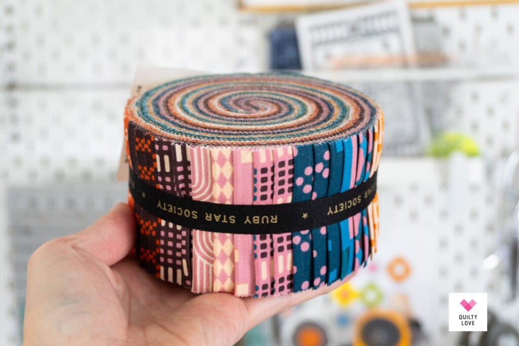 Colorful fabric roll with various quilt patterns for quilting projects.