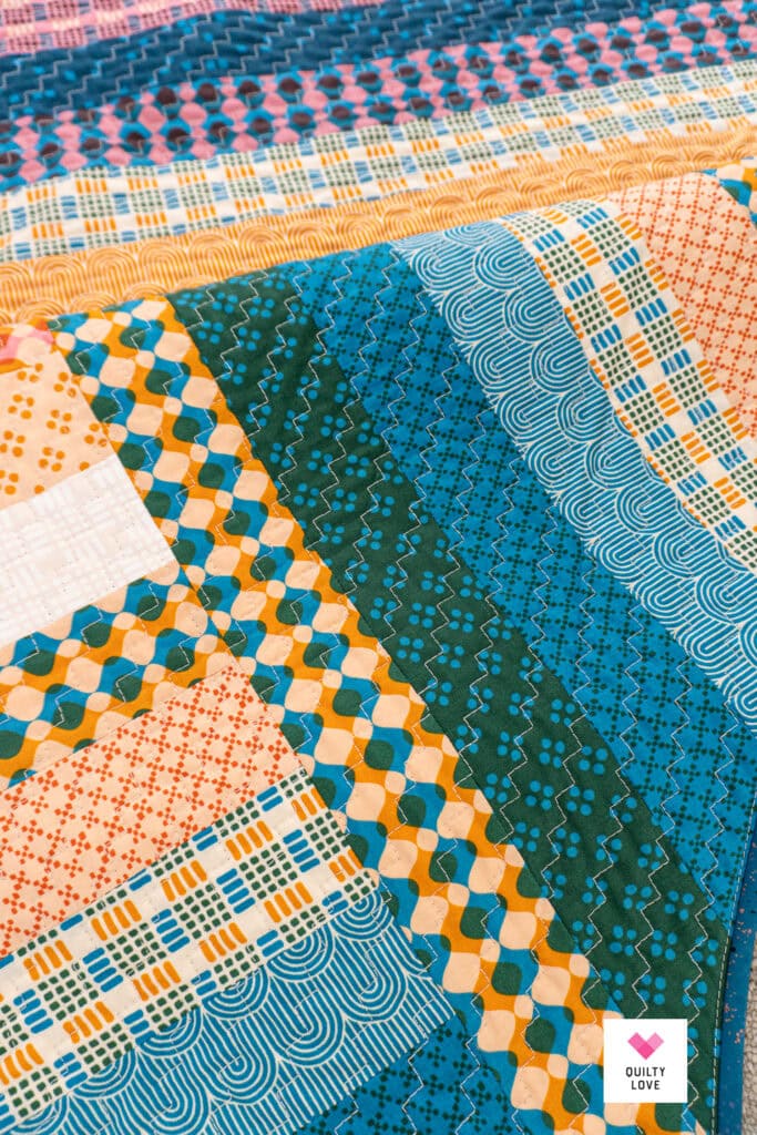 Vibrant patchwork quilt with geometric and floral patterns in blue, orange, and white.