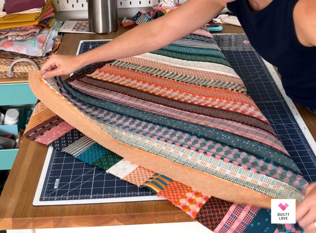 Person selecting vibrant quilt fabric strips for quilting project.