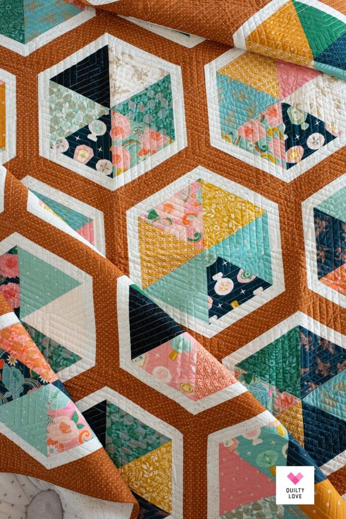 A hexie quilt with white sashing and a brown background