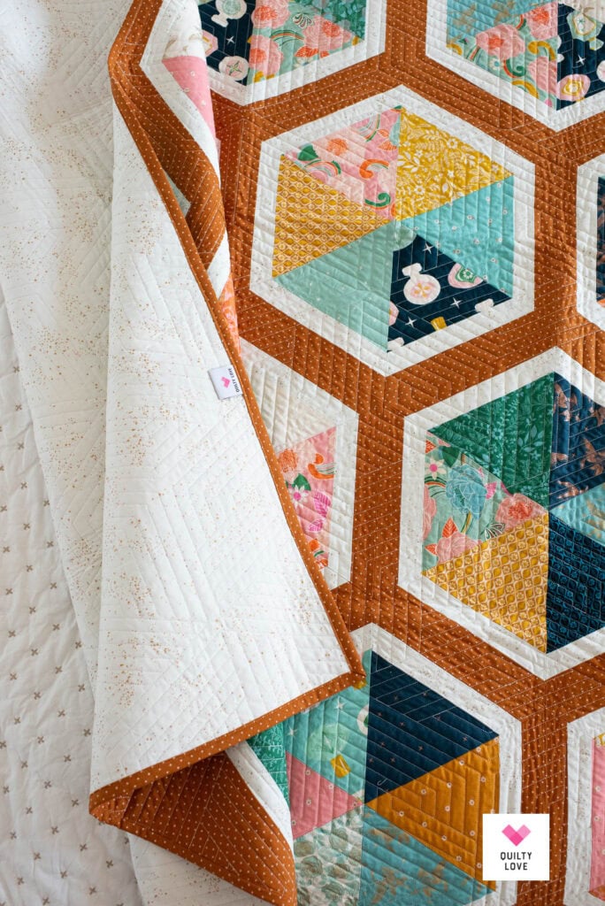 A Triangle Hexies quilt showing the front, back and binding